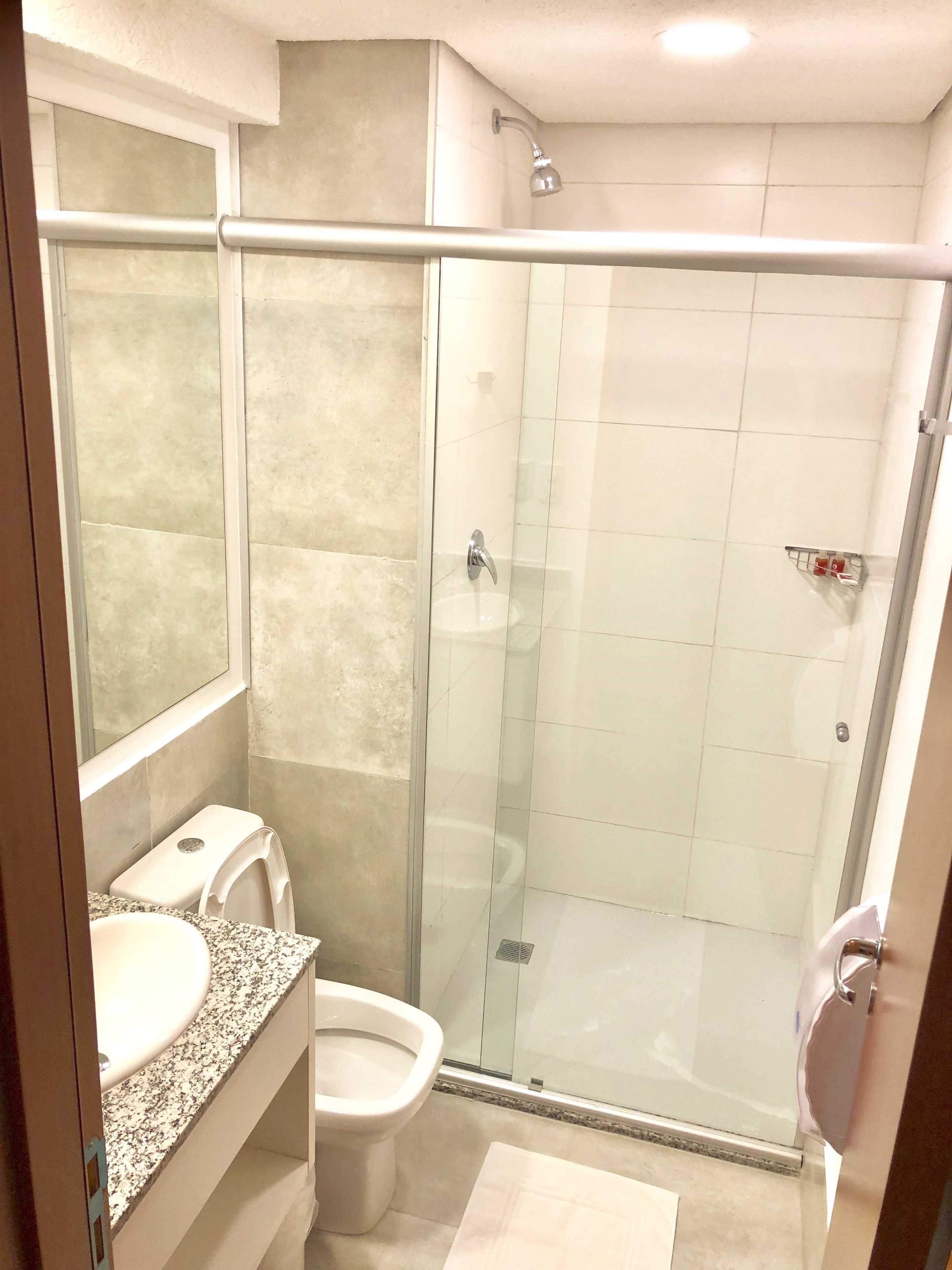 A modern bathroom with a glass-enclosed shower, a sink, and a toilet.
