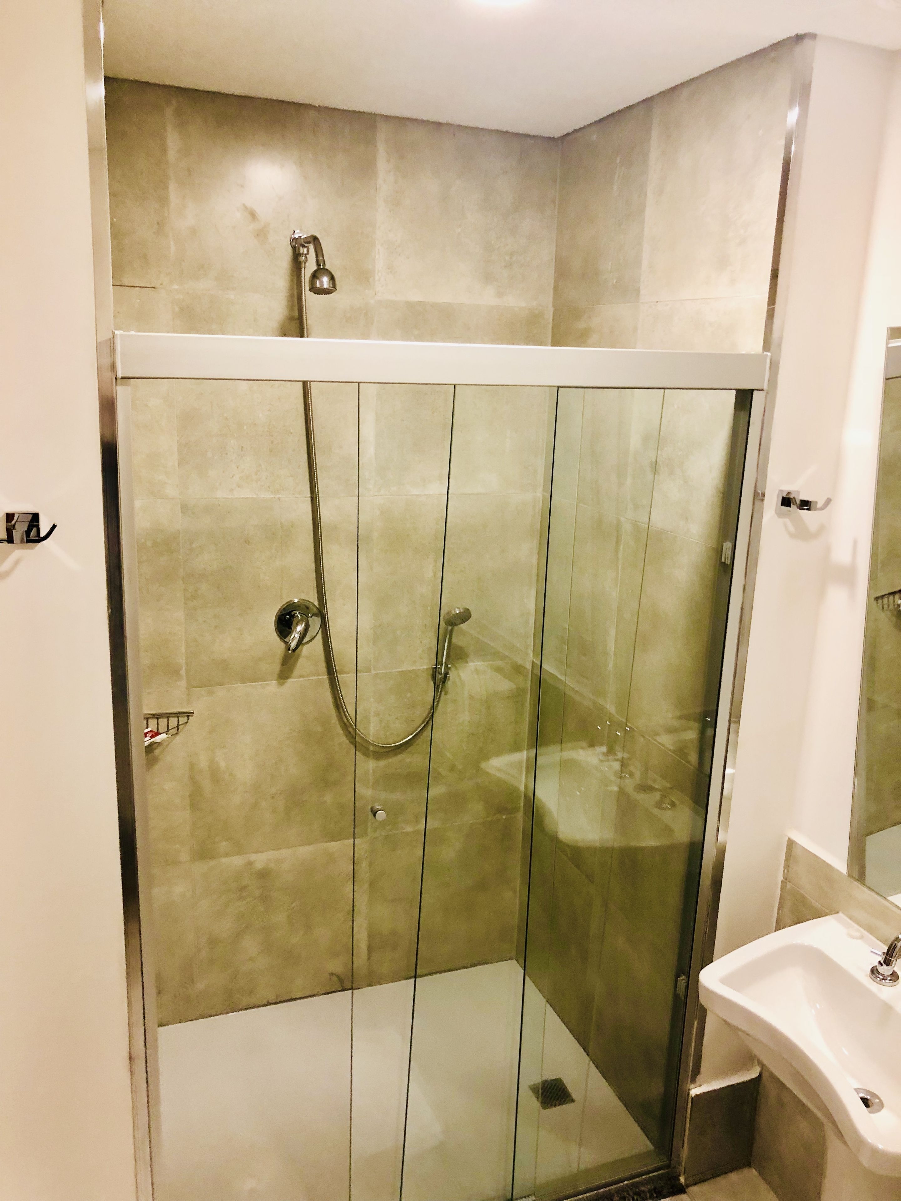 A modern bathroom with a glass-enclosed shower, a white sink, and a mirror.