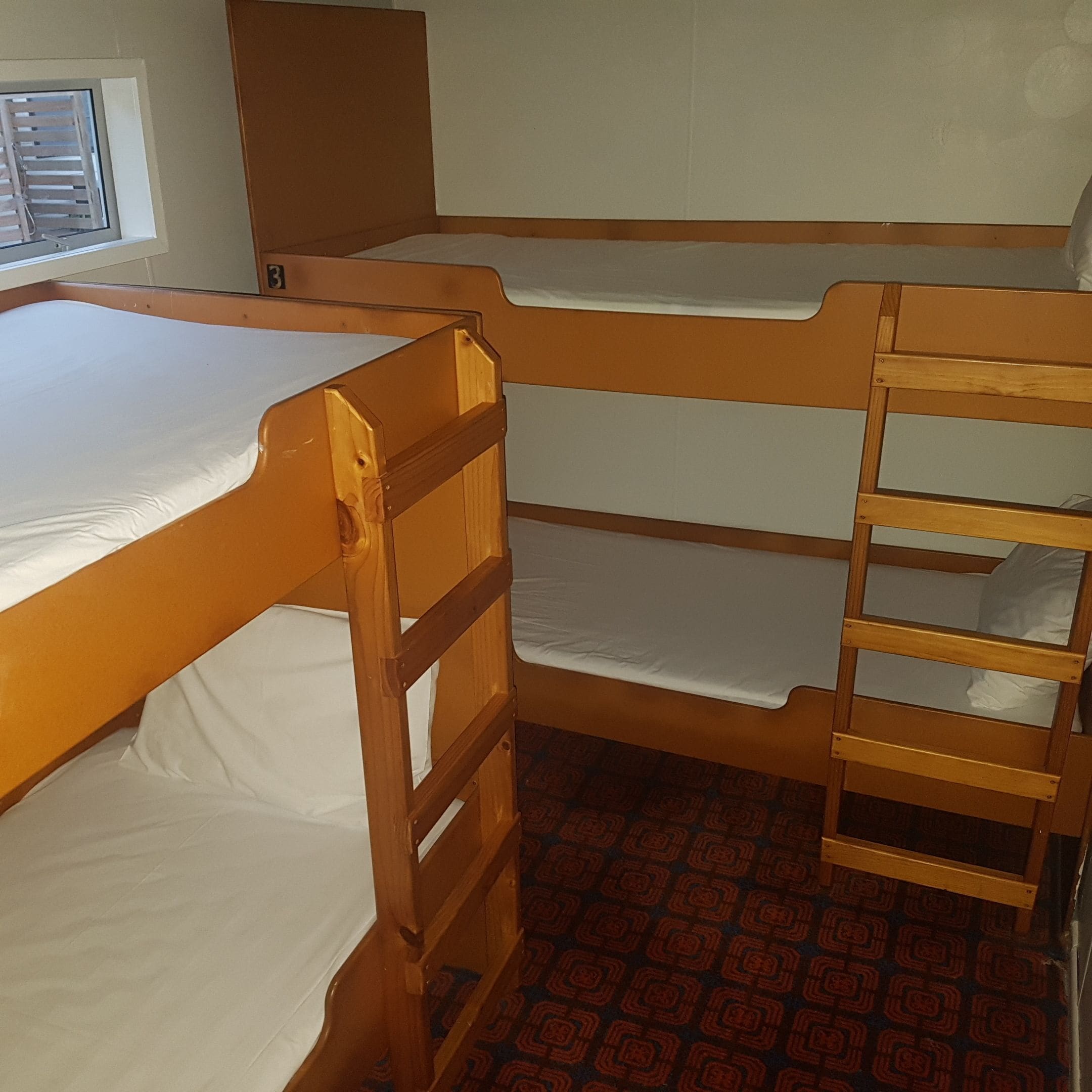 Ein Schlafzimmer mit Etagenbetten, Holzrahmen und weißer Bettwäsche.