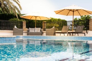 Een buitenzwembad en ligstoelen