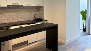 A modern kitchen with a black countertop, white cabinets, and pendant lighting. - Lisbon City Inn Hotel by City Hotels (Lisbon)