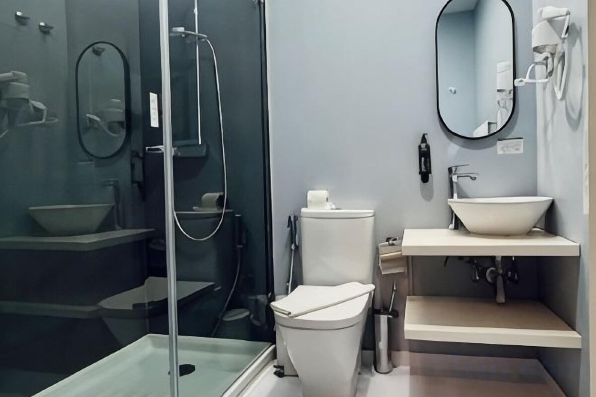 A modern bathroom with a glass-enclosed shower, a toilet, a sink, and a mirror.