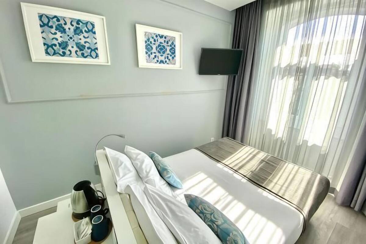 Una camera d'albergo con un letto, una TV a schermo piatto e due opere d'arte appese alla parete.