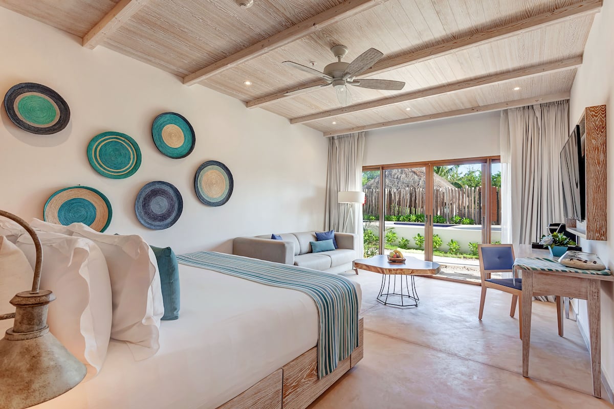 Quarto moderno com uma cama grande, ventilador de teto e vista para o exterior.