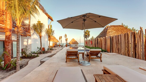 A beachside lounge area with sun loungers, wooden tables, and umbrellas. - Mystique Holbox by Royalton, A Tribute Portfolio Resort (Isla Holbox)