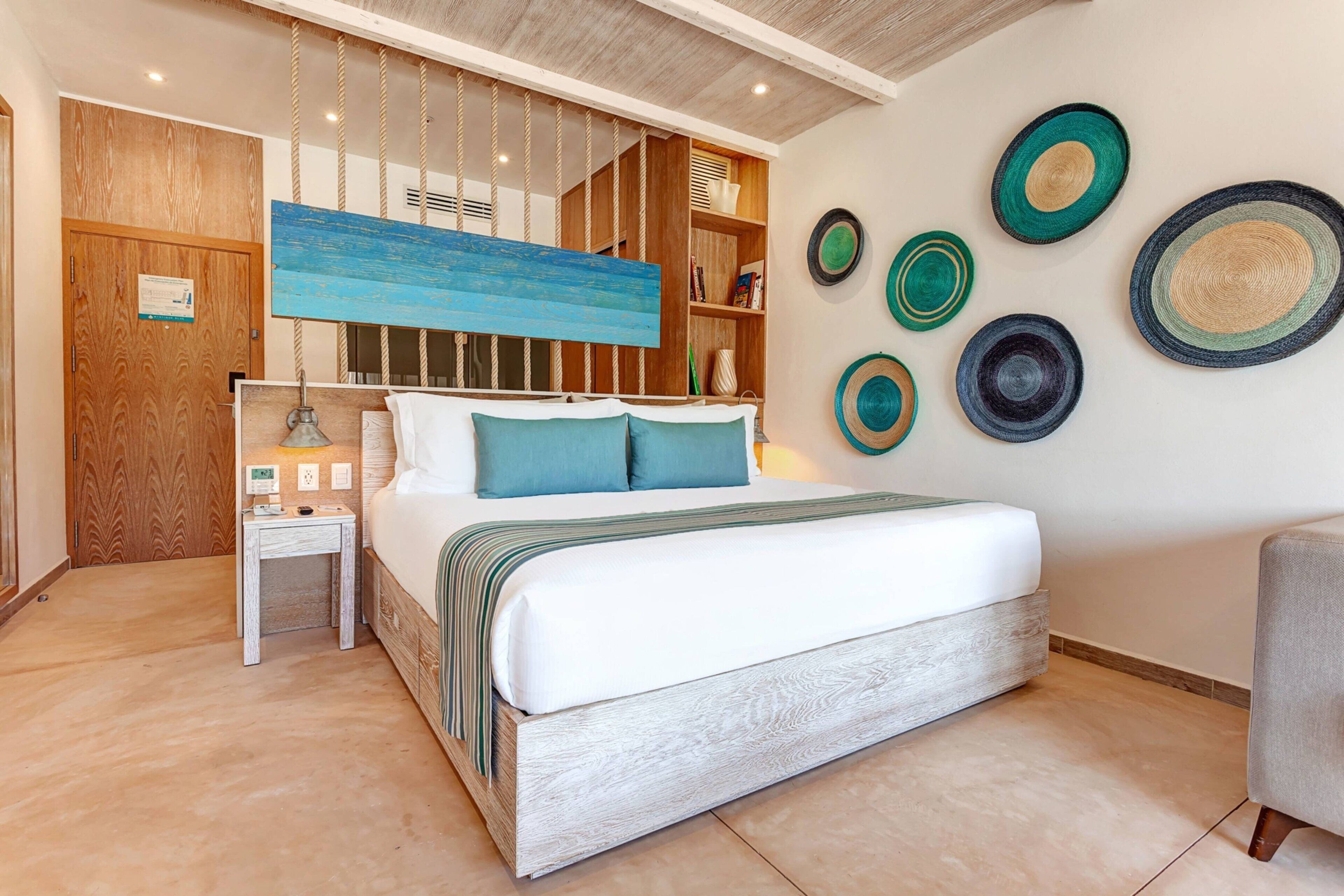 A bedroom with a bed, bedside table, and a wall with decorative plates.