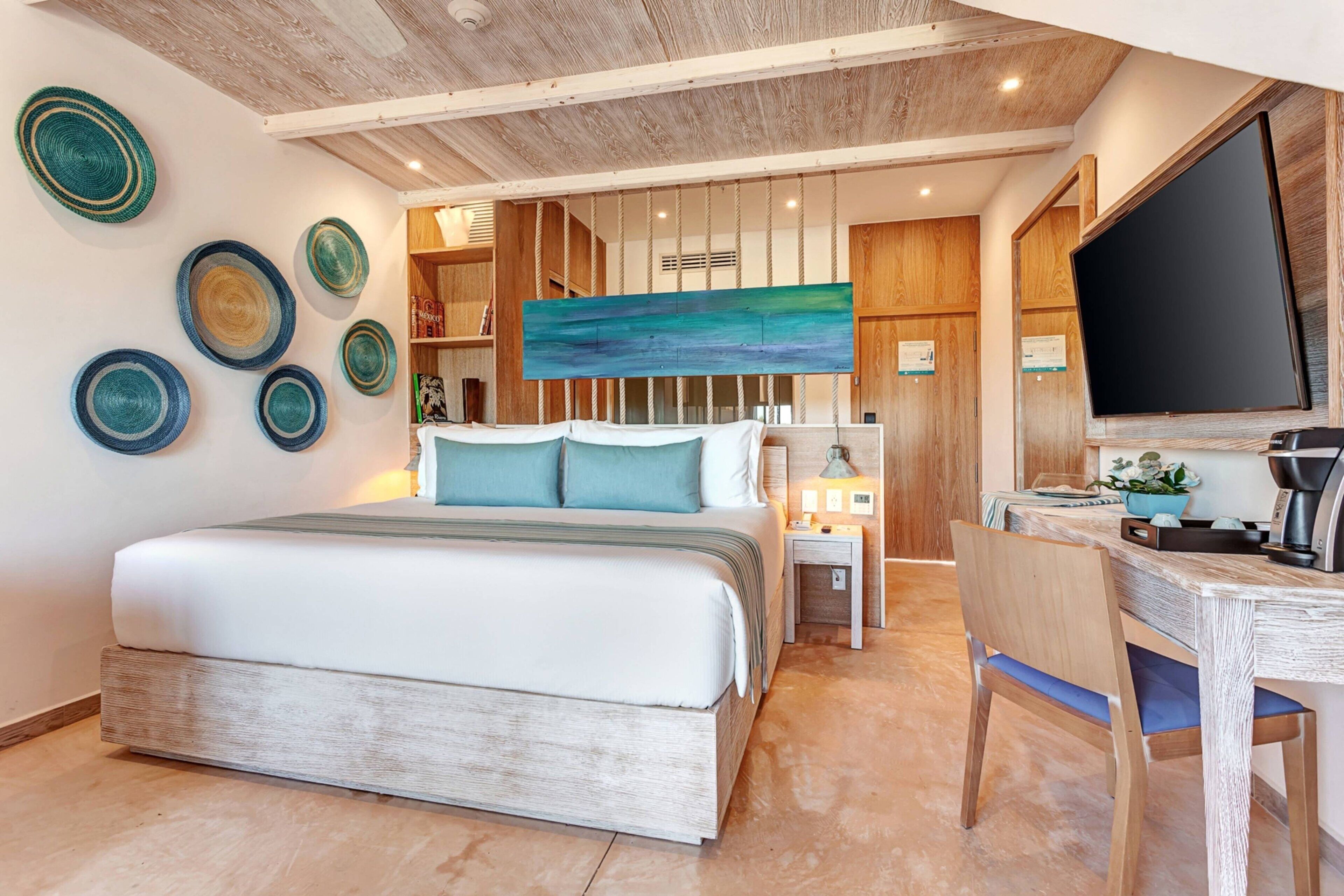 A bedroom with a bed, a desk, and a TV. There are decorative plates on the wall.