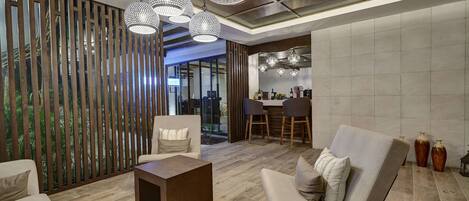 A modern living room with a sofa, a coffee table, and a dining area with chairs and a table.