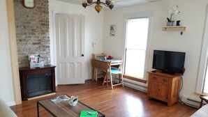 Una sala de estar con chimenea, televisor, mesa de centro de madera y ventana con persianas.