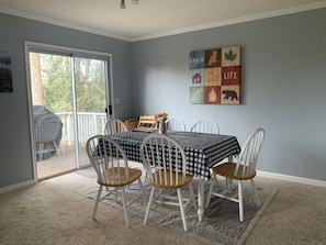 A dining area with a checkered tablecloth, white chairs, and a decorative wall piece.