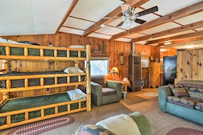 A cabin with bunk beds, a sofa, a small table, and a refrigerator.