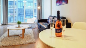A modern living room with a sofa, a round table, and two glasses of rosé wine. - Premier Stays Melbourne (Southbank)