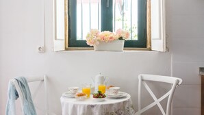 A breakfast setup with a table, chairs, and a window with flowers. - ★Romantic - Casa Bela ★ Apartment with private terrace and shared garden (Porto)