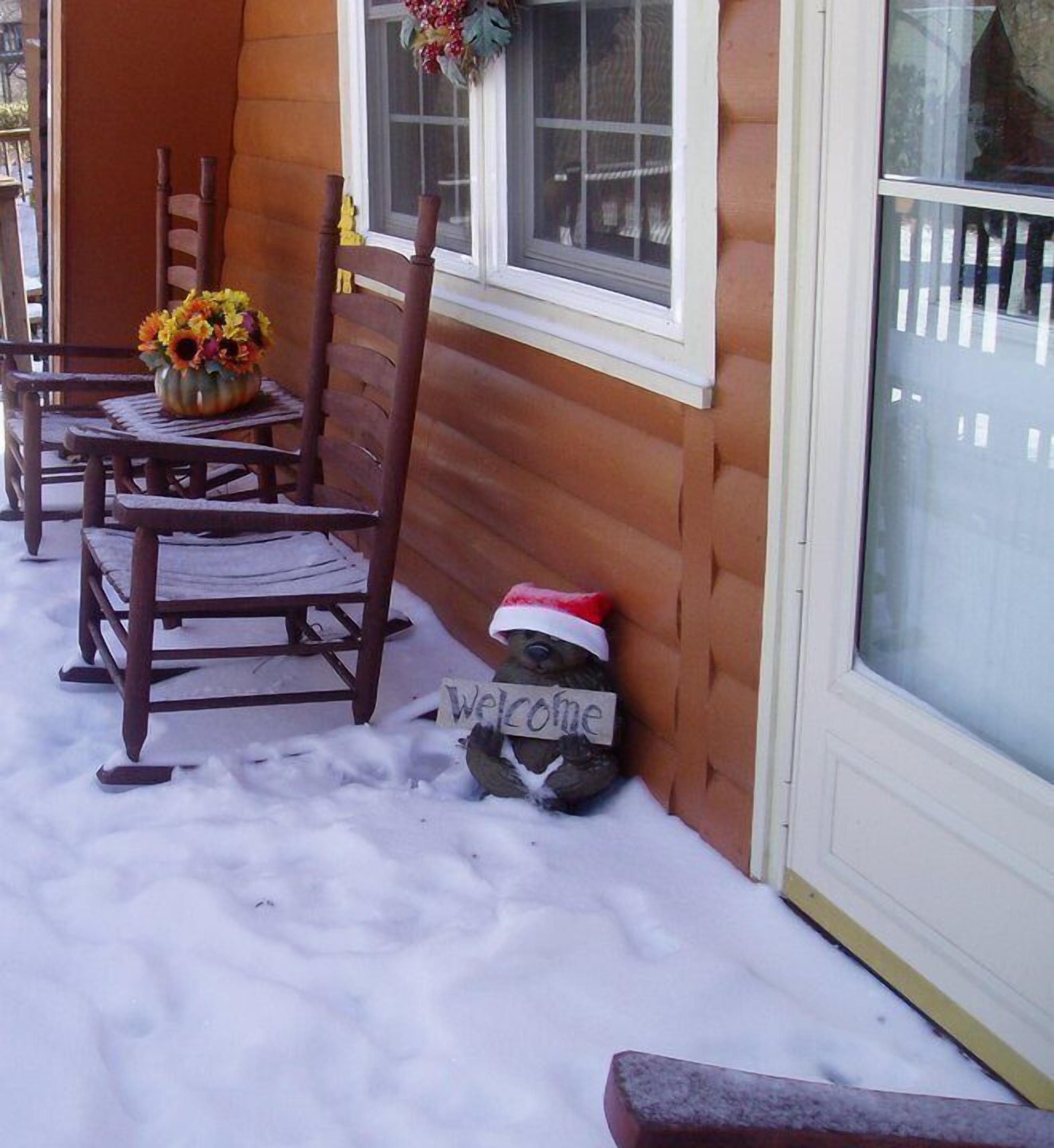 A wooden cabin with a porch, a welcome sign, and a vase of flowers.