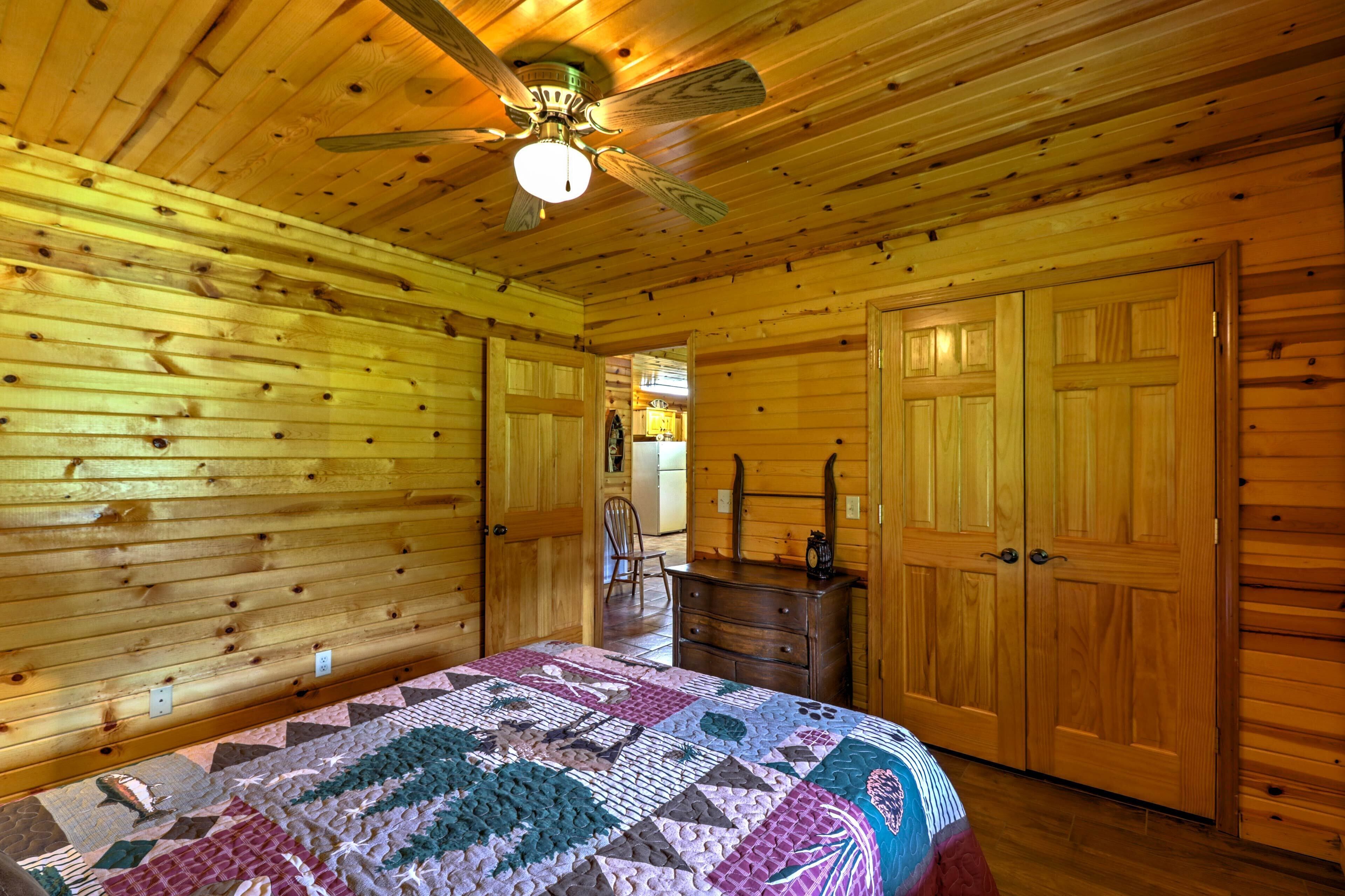A wooden cabin bedroom with a bed, dresser, and wardrobe.