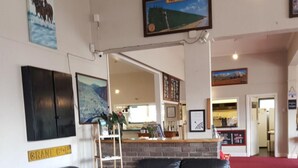 A hotel lobby with a black leather sofa, a wooden coffee table, a brick wall, and a red carpet. - Hampden Hotel (Murchison)