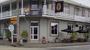 A two-story building with a sign for Hampden Hotel, offering accommodation, bistro meals, fish & chips, bar, and a bottle store. - Hampden Hotel (Murchison)