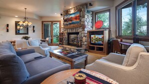 A spacious living room with a stone fireplace, comfortable seating, and large windows offering natural light. - CX311 | Walk to Mtn Village | Ski In/Out | Winter Shuttle | Pool | Hot Tub (Steamboat Springs)