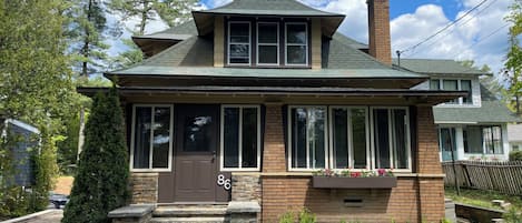Une maison à deux étages avec une porte marron, de grandes fenêtres et une façade en briques.