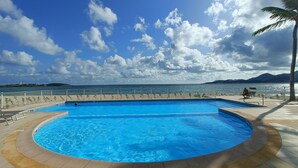 A large outdoor swimming pool with a view of the sea and mountains in the background. - Friendly Beach House (4160 nettle baie beach club)