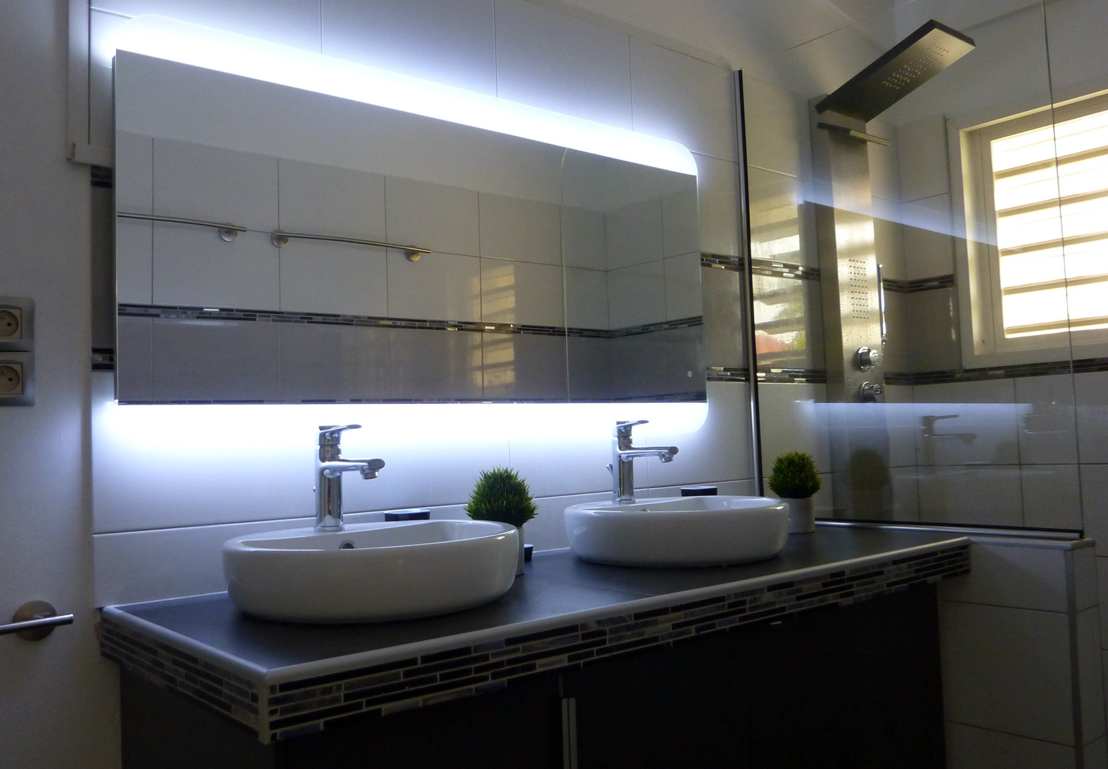 Une salle de bain avec deux lavabos, un grand miroir et une fenêtre.