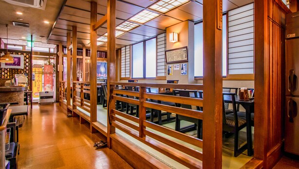 A restaurant with wooden railings, tables, and chairs. There are signs on the walls and a menu board. - Tabist Hotel Fuji (Daisen)
