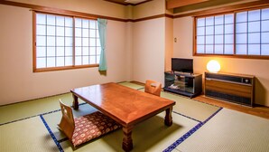 A traditional Japanese room with tatami flooring, a wooden table, a television, and a heater. - Tabist Hotel Fuji (Daisen)