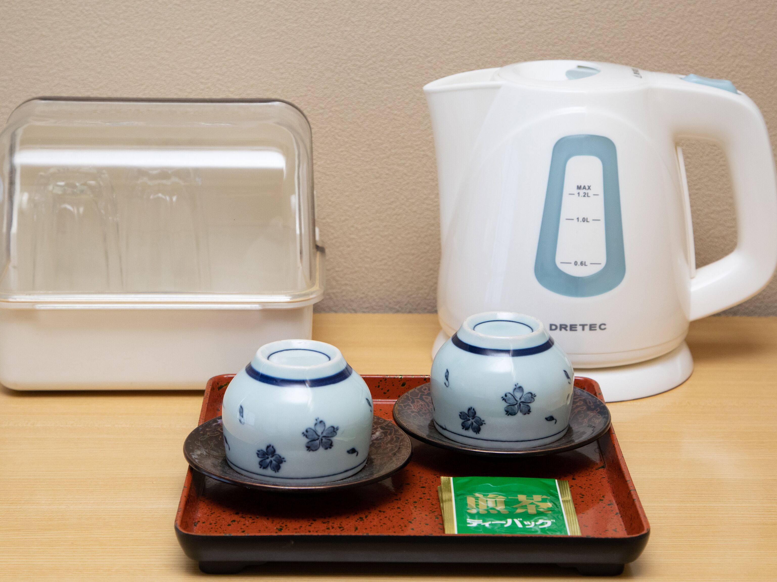 Un espai cuina amb un recipient transparent, un búllet elèctric blanc i dues tasses de ceràmica sobre un safata.