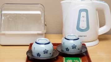 Un espai cuina amb un recipient transparent, un búllet elèctric blanc i dues tasses de ceràmica sobre un safata.