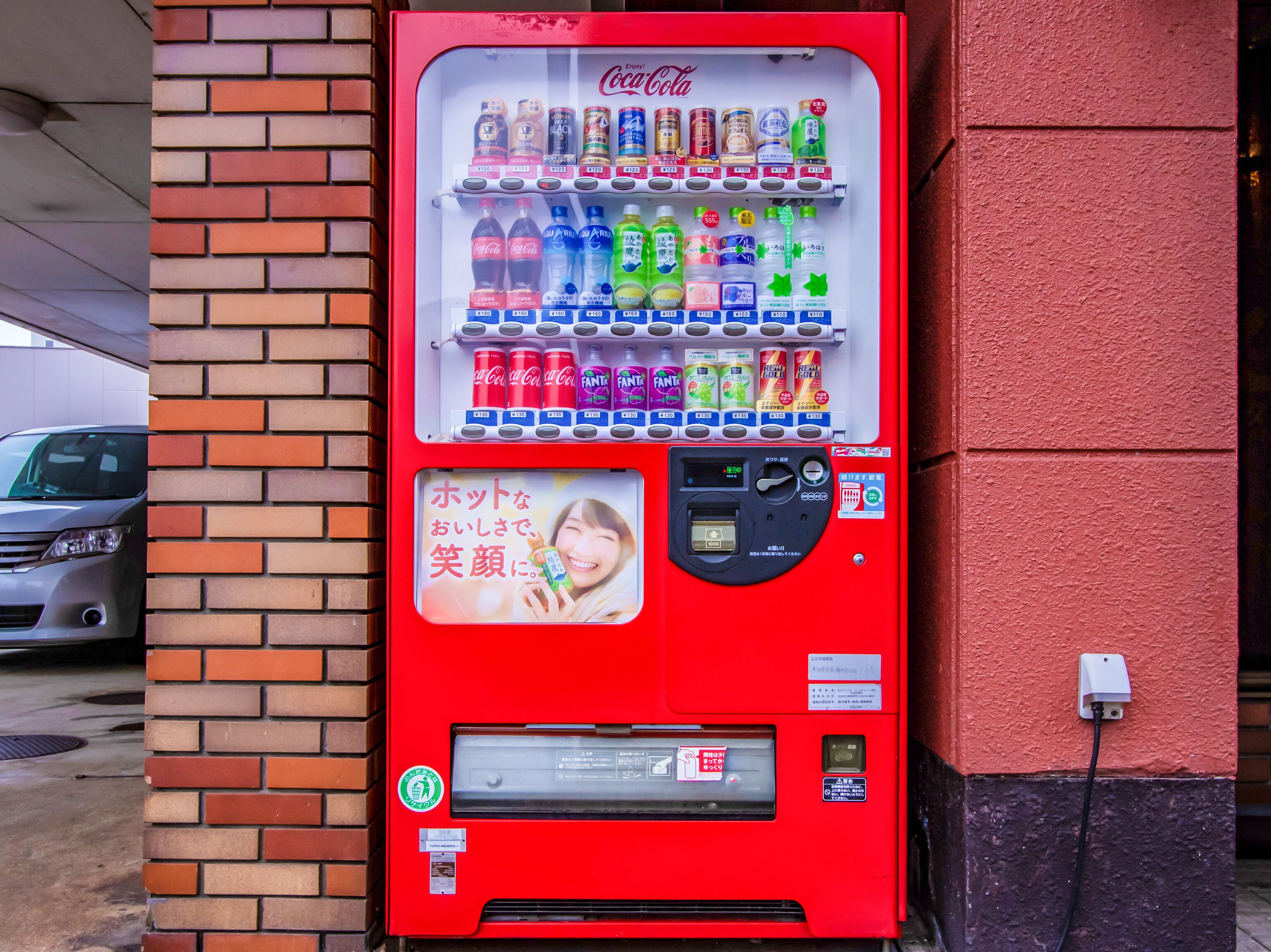 Una máquina expendedora roja con diversas bebidas y una ranura para pagos.