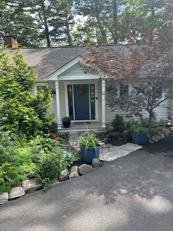 A house with a front porch, a small garden, and a driveway.