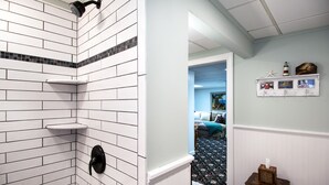 A bathroom with white subway tiles, a black showerhead, and a small shelf. - Quiet Riverfront getaway to enjoy Midcoast Maine! (Damariscotta)