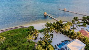 A tropical beach resort with a pool, palm trees, and a pier extending into the ocean. - PRIVATE BEACHFRONT PARADISE with COOK & POOL = Luxury on the Sea! (San Pedro)