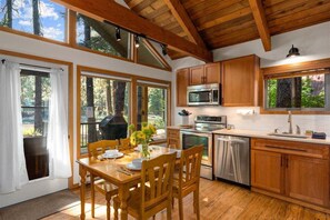 A kitchen with wooden cabinets, stainless steel appliances, and a dining area with a table and chairs.