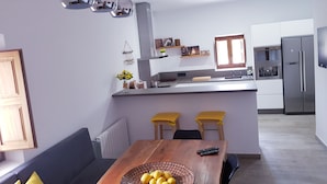 Una cucina moderna con isola centrale, elettrodomestici in acciaio inossidabile e zona pranzo con tavolo in legno e sedie gialle.