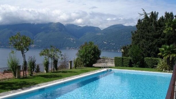 A swimming pool with clear blue water, surrounded by a well-maintained lawn and a view of mountains and a lake. - Cordelia 6 with lake view, balcony and pool (Luino)