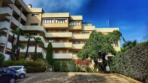 A multi-story residential building with balconies, surrounded by greenery and a parking area. - Cordelia 6 with lake view, balcony and pool (Luino)