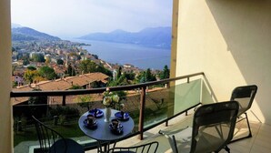 A balcony with a table set for two, overlooking a lake and a town. - Cordelia 6 with lake view, balcony and pool (Luino)