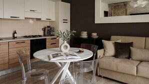 Eine moderne Küche mit weißen Schränken, einem Esstisch mit Stühlen, einem Sofa und einem großen Spiegel.