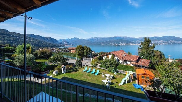 A balcony with a view of a lake, mountains, and a garden with outdoor furniture. - India apartment with lake view over Stresa (Stresa)