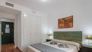 Un dormitorio con cama, mesita de noche, lámpara, un cuadro y armario.