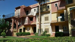 Un edificio de varios pisos con balcones, un c ésped bien cuidado y un cielo despejado.