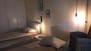 A bedroom with two beds, a bedside table, a lamp, and a woven basket. - Casa al Vecchio Porto overlooking the ancient port (Cannero Riviera)
