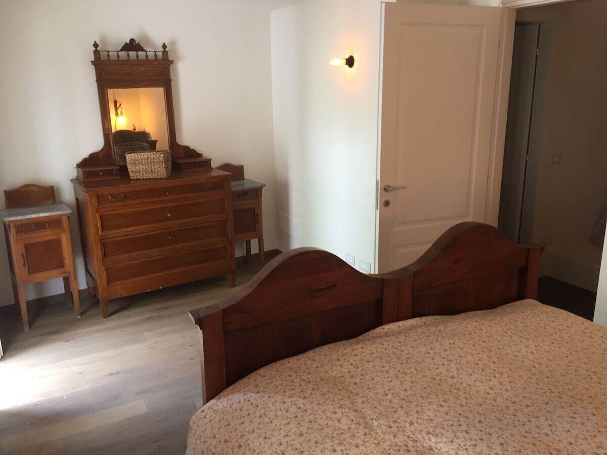 A bedroom with a wooden bed, a dresser, a mirror, and a door.