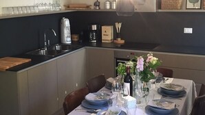 A modern kitchen with a dining area set for a meal. - Casa al Vecchio Porto overlooking the ancient port (Cannero Riviera)