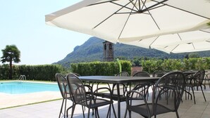 Un espace extérieur aménagé pour les repas, avec une piscine, des chaises et des parasols.