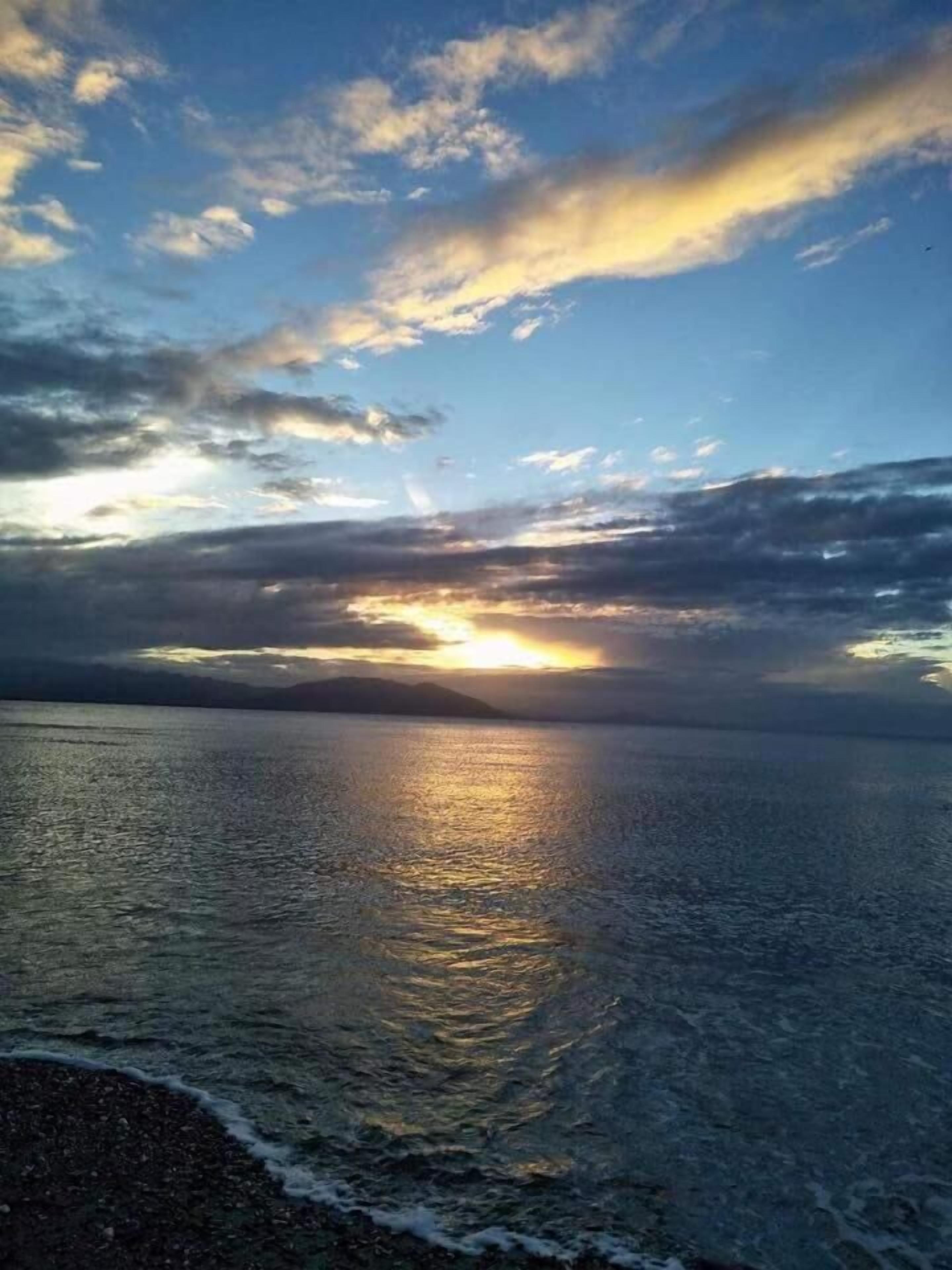 Un atardecer sobre un mar tranquilo con cielo despejado.