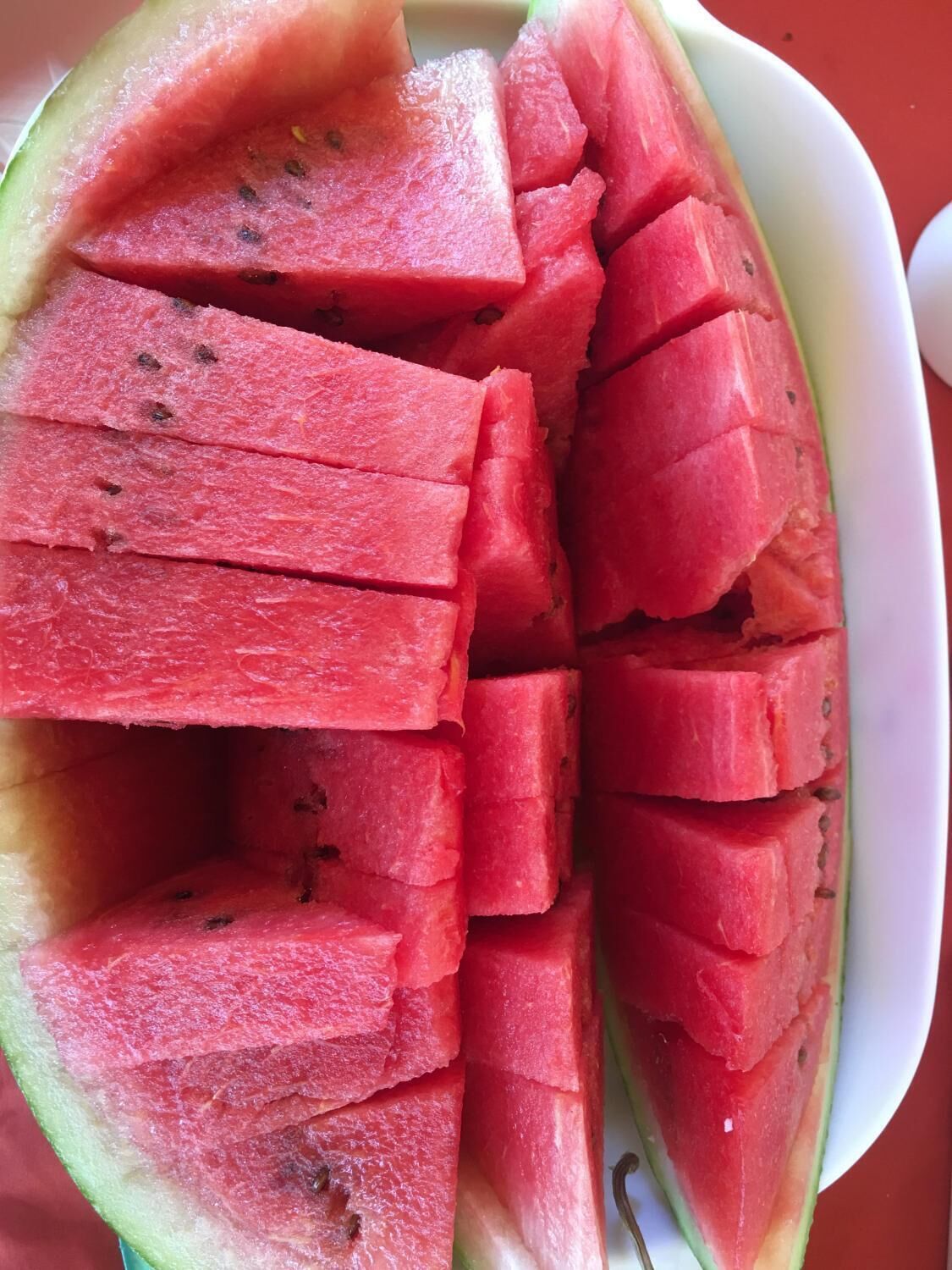 A white plate with neatly cut watermelon pieces.