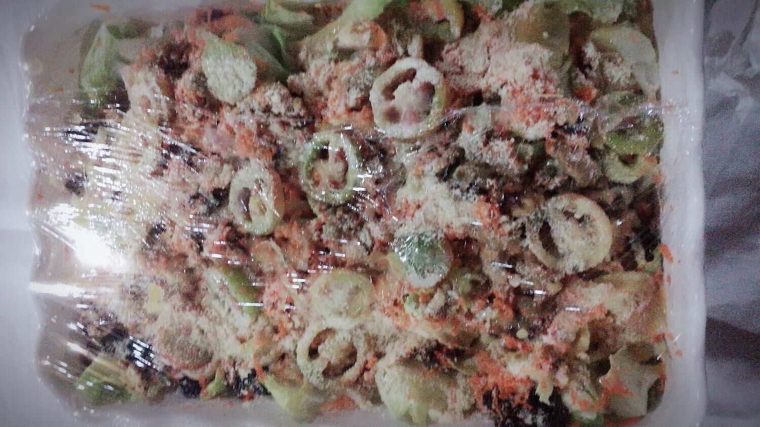 A meal in a plastic container with various vegetables and a creamy sauce.