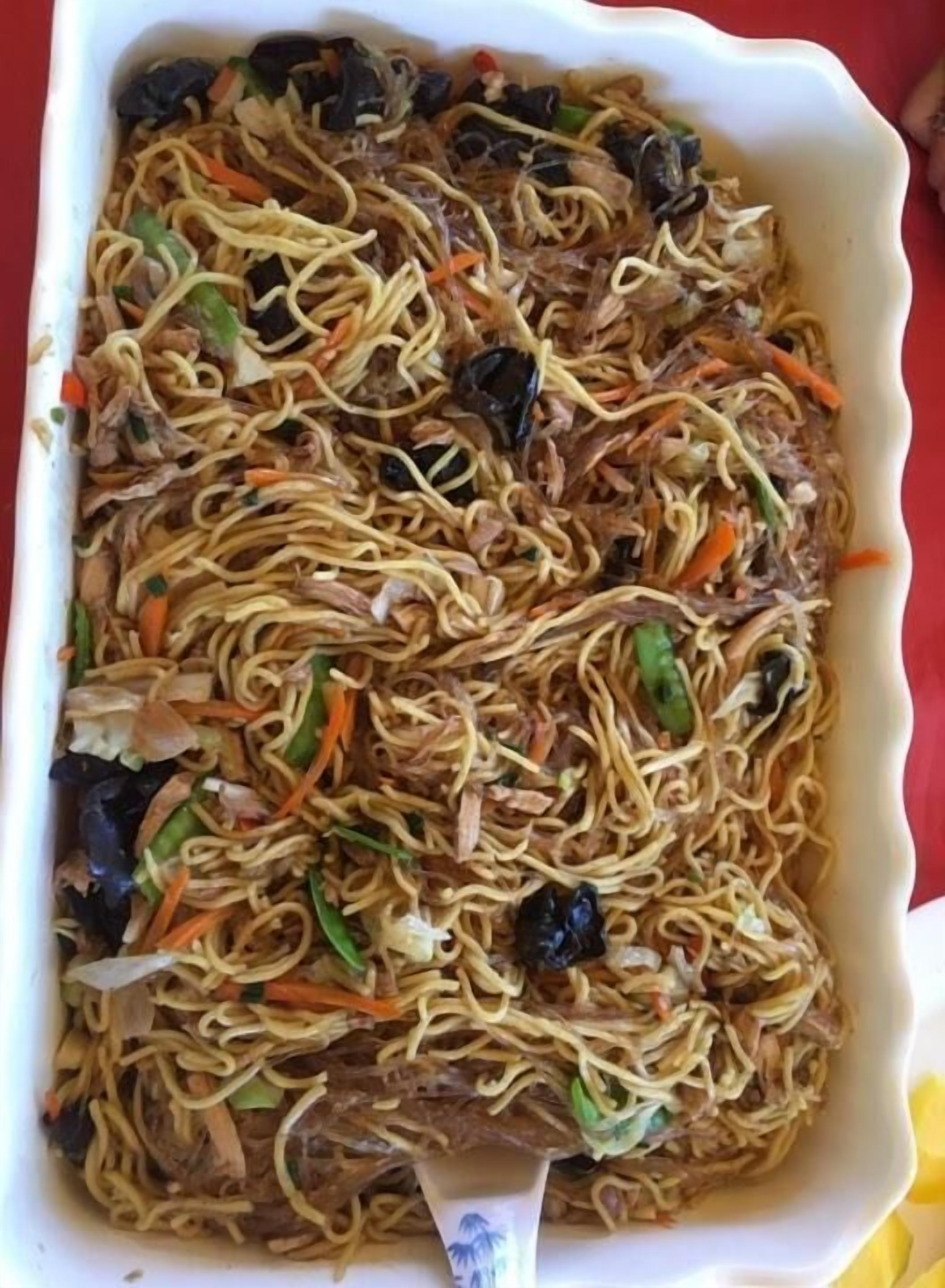 A rectangular white dish filled with noodles, vegetables, and meat.